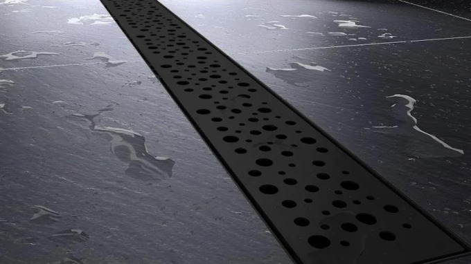 Sprchový žlab s černou dekorační mřížkou ve tvaru koleček pro elegantní vzhled a odolnost