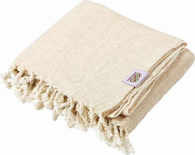 Ručně tkaná vlněná deka v příjemné béžové barvě, která připomíná odstín slonové kosti, s decentním vzorkem a možností použití jako přehoz přes postel či gauč